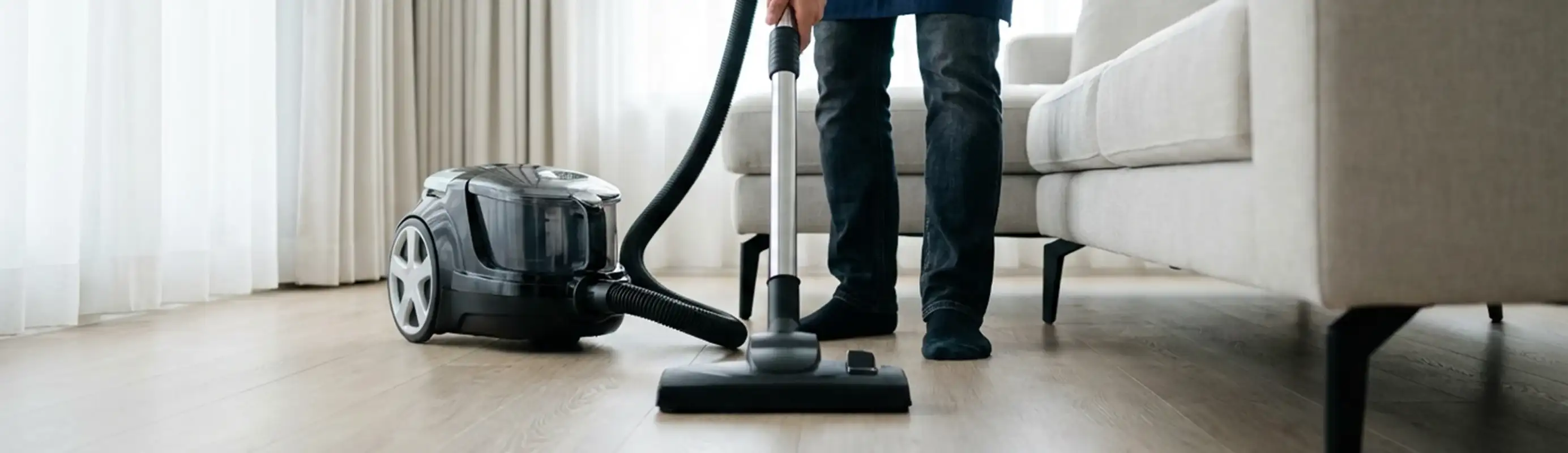Professional house cleaner vacuuming a living room floor with a canister vacuum cleaner, Louisville, KY.