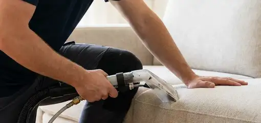 Professional upholstery cleaner deep-cleaning a fabric sofa with a handheld extraction tool, Louisville, KY.